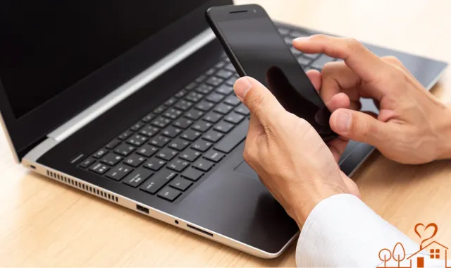 PCの前でスマホを手にする人物の手