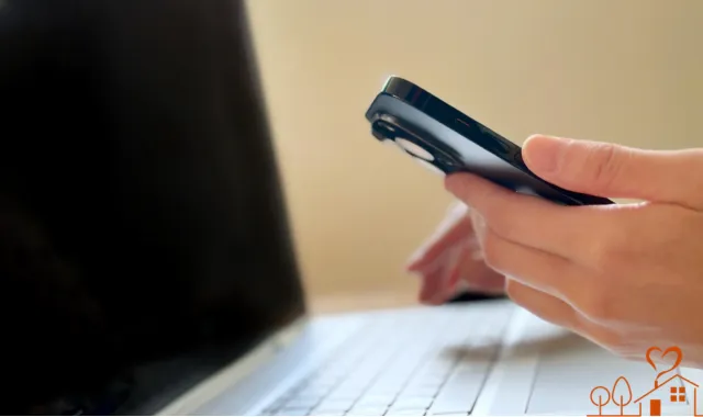 スマホを片手にパソコンに向かう人物
