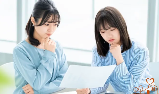 資料を見て考え込む女性2人