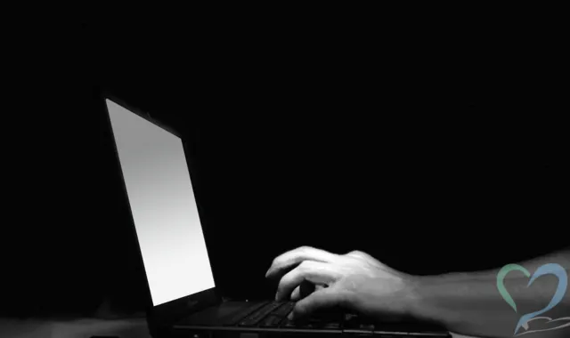 暗闇の中でパソコンを触る人