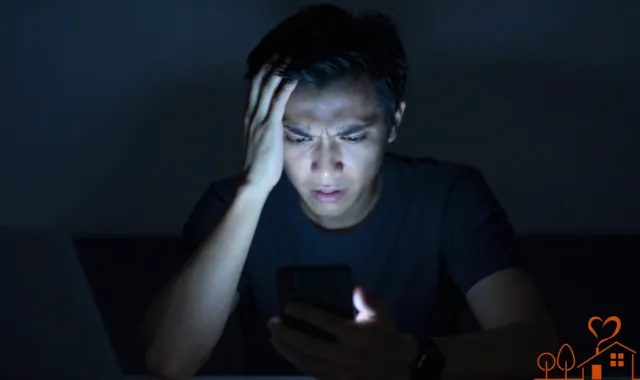 携帯を見て頭を抱える男性